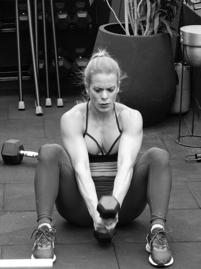 Woman exercising with dumbbells, promoting wellness and fitness in grayscale.